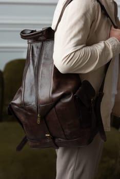 A man in a beige shirt posing with a brown backpack