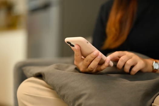 Cropped shot unrecognizable young woman scrolling social media on mobile phone.