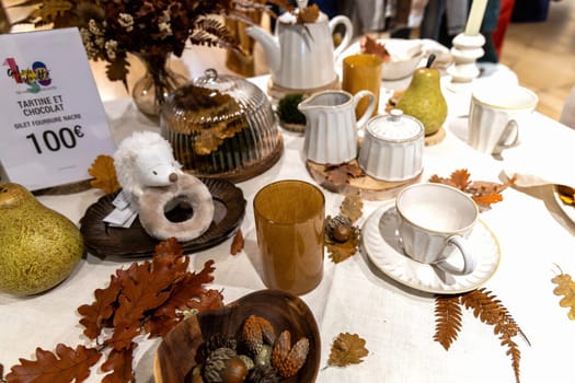 Autumn table setting with white cups and yellow oak leaves on the table. Paris, France - Oktober 25, 2024