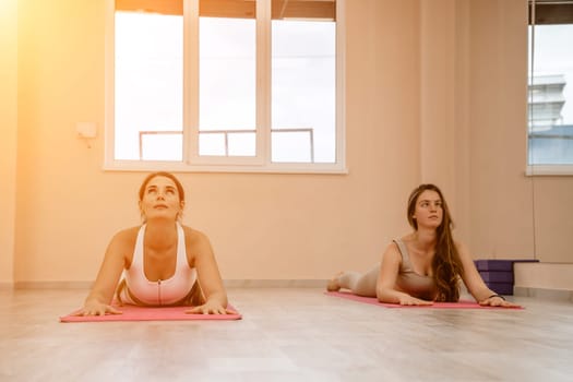 Two beautiful women do yoga, sports in the gym. The concept of grace and beauty of the body