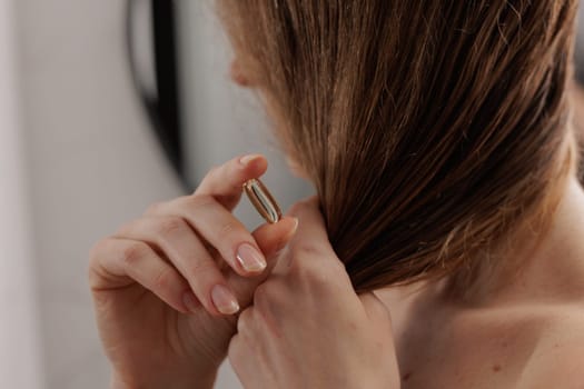 Close up of woman hand showing Omega 3 capsule for healthy hair, vitamins for hair care