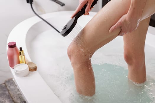 Unrecognizable woman washes the foam off her feet in the shower,