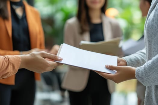 A manager is seen handing a booklet to a small team of employees in a bright and modern office. The scene captures a moment of collaboration and support.