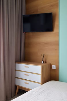 This stylish and modern bedroom boasts a wallmounted television, elegant curtains, and chic contemporary furnishings