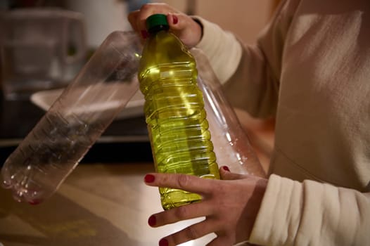A close-up view of someone handling empty plastic bottles and one containing a yellow liquid