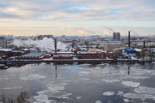 A captivating and stunning winter view featuring an industrial area beautifully reflecting on a river with floating ice