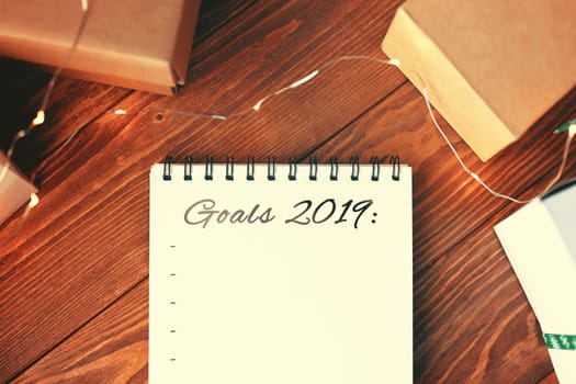 Prepare for Christmas with Notepad and gifts. Notebook with the words Goals 2019 lies on a wooden table. Close up.