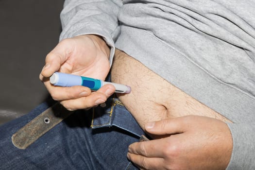 Diabetic man injects himself with Ozempic Insulin injection pen for diabetics.
