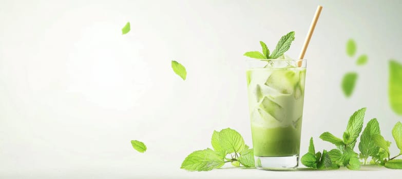 Iced matcha tea in a tall glass with a bamboo straw, surrounded by fresh mint leaves. a clean, bright white background provides ample space for branding or design elements, the drink's vibrant color and refreshing appeal.