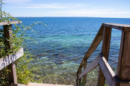 View of the blue sea on a quiet summer sunny day. Stairs to the sea. High quality photo