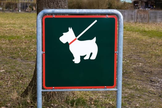 A sign in the park that means walking the dog only on a leash. High quality photo