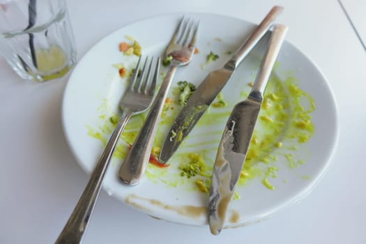 A thoroughly messy plate accompanied by used cutlery after savoring a delicious meal