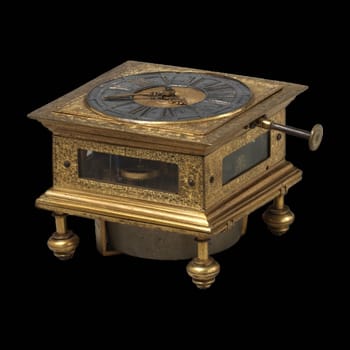 A close-up of an antique 17th-century German brass table clock by Johann Heinrich Kleinschmidt, showcasing intricate details and a timeless design