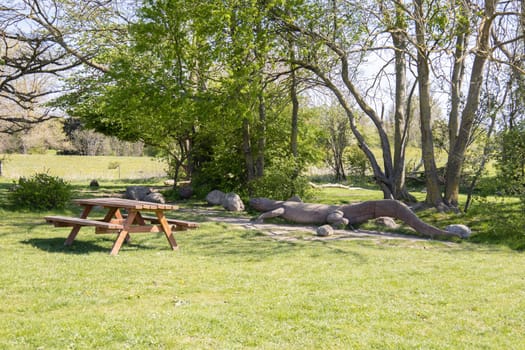 Summer park for outdoor activities with a bench and a large wooden crocodile. High quality photo