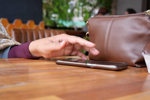 A hand grabbing and picking up mobile phone on the table
