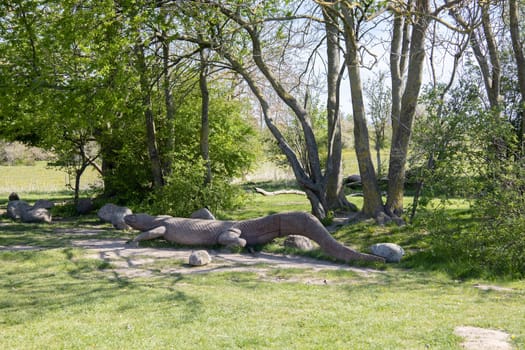 Summer park for outdoor activities with a bench and a large wooden crocodile. High quality photo