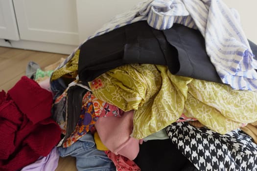 Disorganized clothing pieces are scattered chaotically across a wooden floor surface