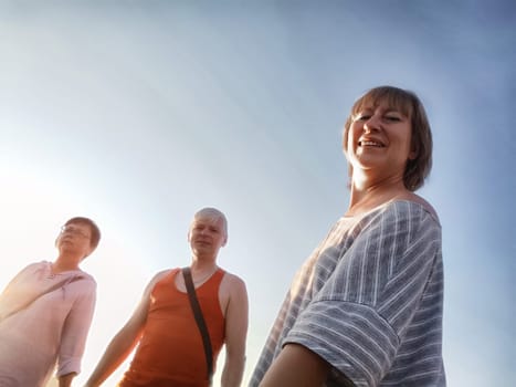 Three friends share a joyful moment outdoors, laughing and connecting under a clear blue sky during a sunny day.