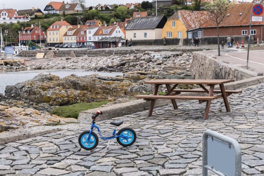Blue children's bicycle on the beach by the sea in a small town. Bornholm, Denmark - December 5, 2024.