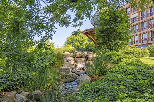 A small waterfall among large stones and green trees. High quality photo