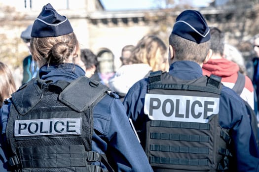 Two policemen, a man and a woman, wearing bulletproof vest with the word police on them. Paris, France - November 1, 2024