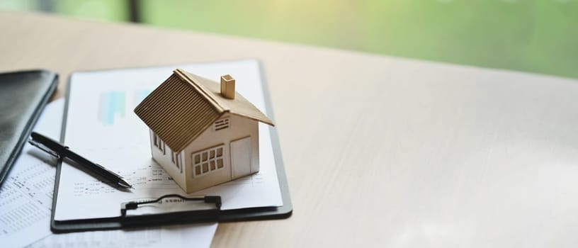 House model and documents on wooden table. Real estate, loan, mortgage and insurance concept.