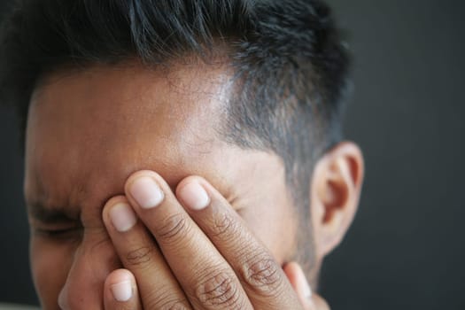 Close up of upset man suffering from strong eye pain.