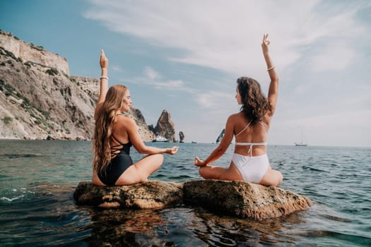 Woman sea yoga. Back view of free calm happy satisfied woman with long hair standing on top rock with yoga position against of sky by the sea. Healthy lifestyle outdoors in nature, fitness concept.