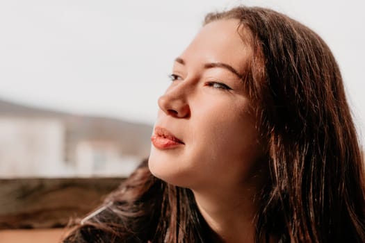 Happy young smiling woman with freckles outdoors portrait. Soft sunny colors. Outdoor close-up portrait of a young brunette woman and looking to the camera, posing against nature background.