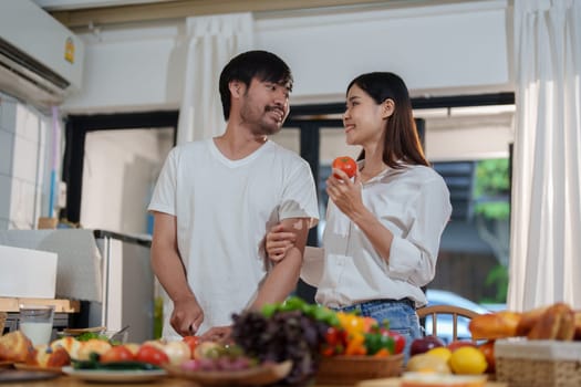 Couple cutting tomatoes for cooking or salad in home kitchen.