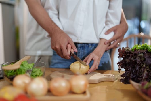 Couple cutting potatoes to cook or make salad in home kitchen