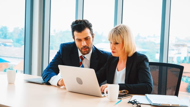 Two business people talk project strategy at office meeting room. Businessman discuss project planning with colleague at modern workplace while having conversation and advice on financial report. Jivy