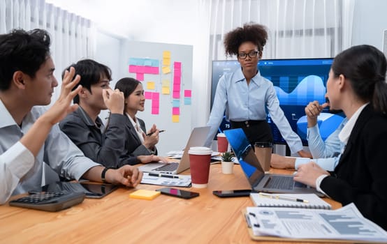 Young african businesswoman presenting data analysis dashboard on TV screen in modern meeting. Business presentation with group of business people in conference room. Concord