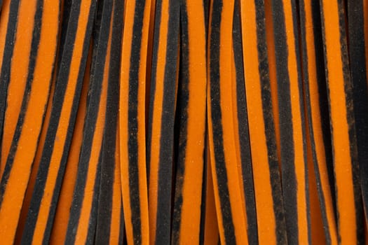 Closeup Black And Orange Pappardelle Italian Pasta, Fresh Wheat Product, Background And Texture. Top View. Egg Dry Ribbon Noodles, Long Rolled Macaroni or Uncooked Spaghetti. Horizontal Macro Flatly.