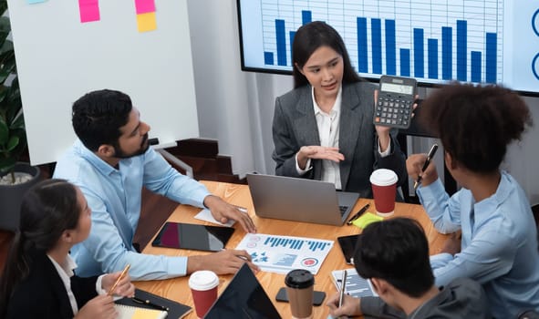 Top view multiracial analyst team use BI dashboard data to analyze financial report on meeting table. Group of diverse business people utilize data analysis by FIntech for business decision. Concord