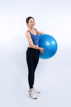 Young attractive asian woman portrait in sportswear with fit ball targeting on abs muscle for effective energetic daily workout routine. Studio shot and isolated background. Vigorous