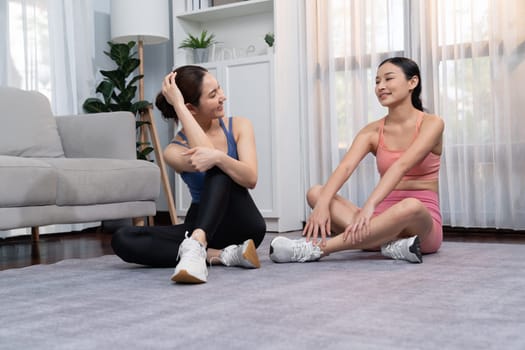 Asian woman in sportswear with her trainer or workout buddy, smiling and posing cheerful gesture. Home workout training or exercise fitness lifestyle in pursuit of healthy lifestyle. Vigorous