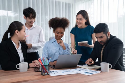 Multiracial analyst team use BI dashboard data to analyze financial report on meeting table. Group of diverse business people utilize data analysis by FIntech for success business marketing. Concord