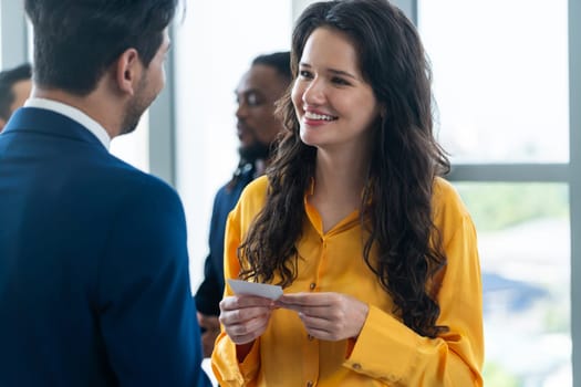 Successful businesswoman holding the name card during talking to manager about their cooperation. Female leader looking businessman during hold his name card admirably. Intellectual.