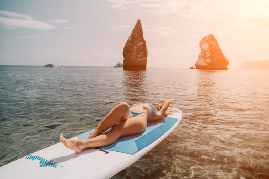 Close up shot of beautiful young caucasian woman with black hair and freckles looking at camera and smiling. Cute woman portrait in a pink bikini posing on a volcanic rock high above the sea