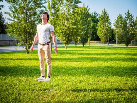 A man standing on top of a lush green field, magically levitating in mid air