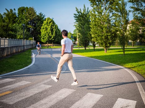 A man is crossing the street in the middle of the road, magically levitating in mid air