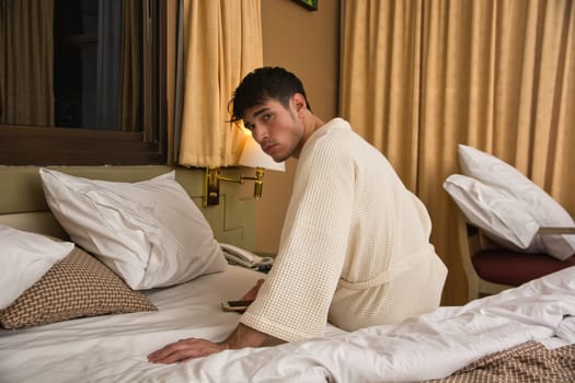 A man sitting on a bed in a hotel room