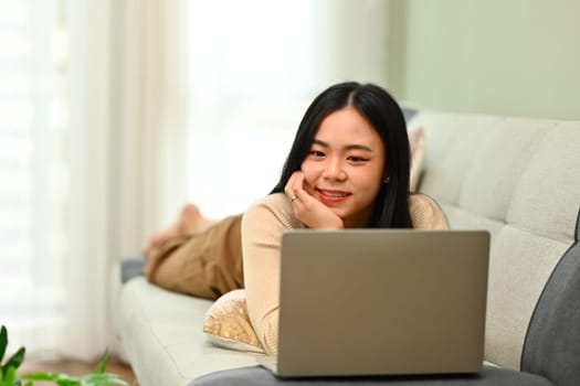 Relaxed young woman browsing internet, watching movie on laptop. People, technology and lifestyle.