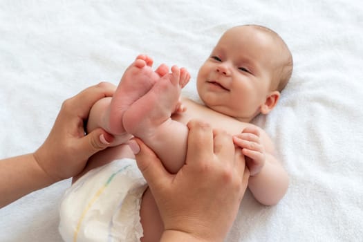 Loving mother plays with her baby, delicately holding the infant's feet in joyous interaction
