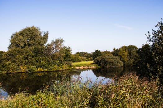 Small quiet lake surrounded by green trees. High quality photo