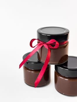 Luxurious chocolate spread jars with red ribbon tied for gift giving elegance.