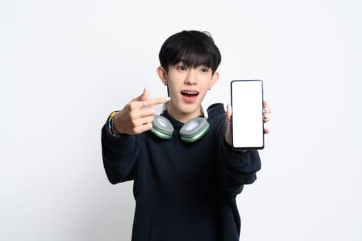 Cute young asian man in hoodie excitedly pointing at smartphone with a blank screen.