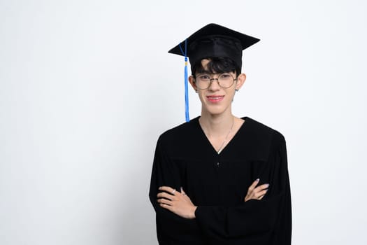 Young male graduate in mortarboard and gown standing with crossed arms. Academic achievement concept.