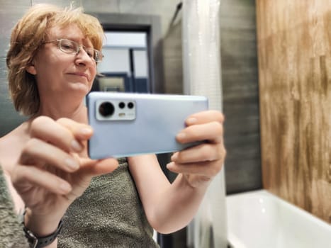 A middle-aged woman captures a candid selfie in her bathroom right after waking up, portraying a relaxed morning vibe.